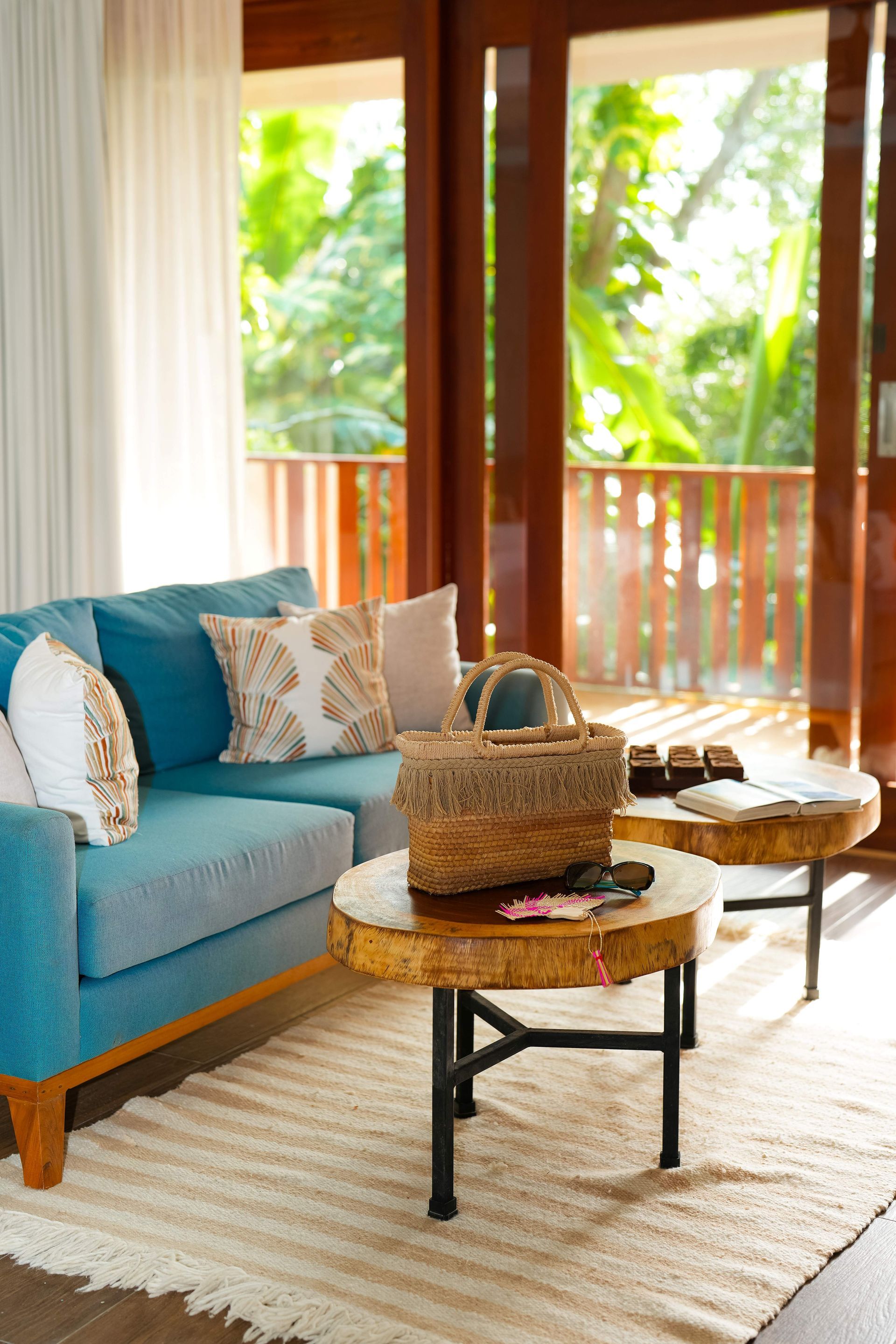 Bright living room with blue sofa, wooden coffee tables, and outdoor view.