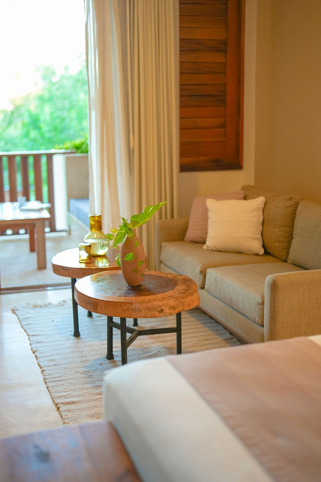 Cozy neutral-toned living space with a sofa, two wooden coffee tables, and a balcony view.
