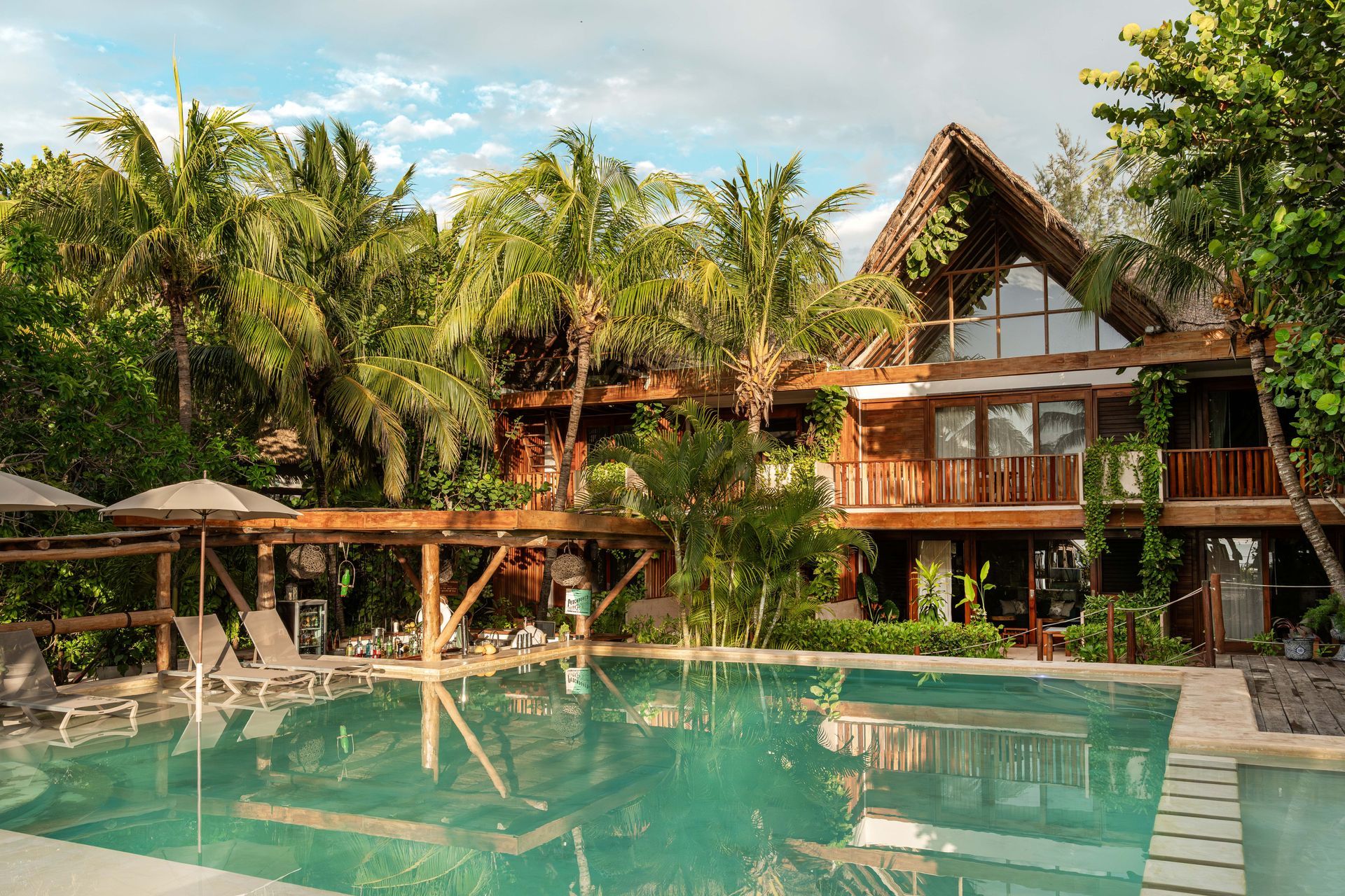 Tropical resort with a pool, wooden buildings, and lush greenery.