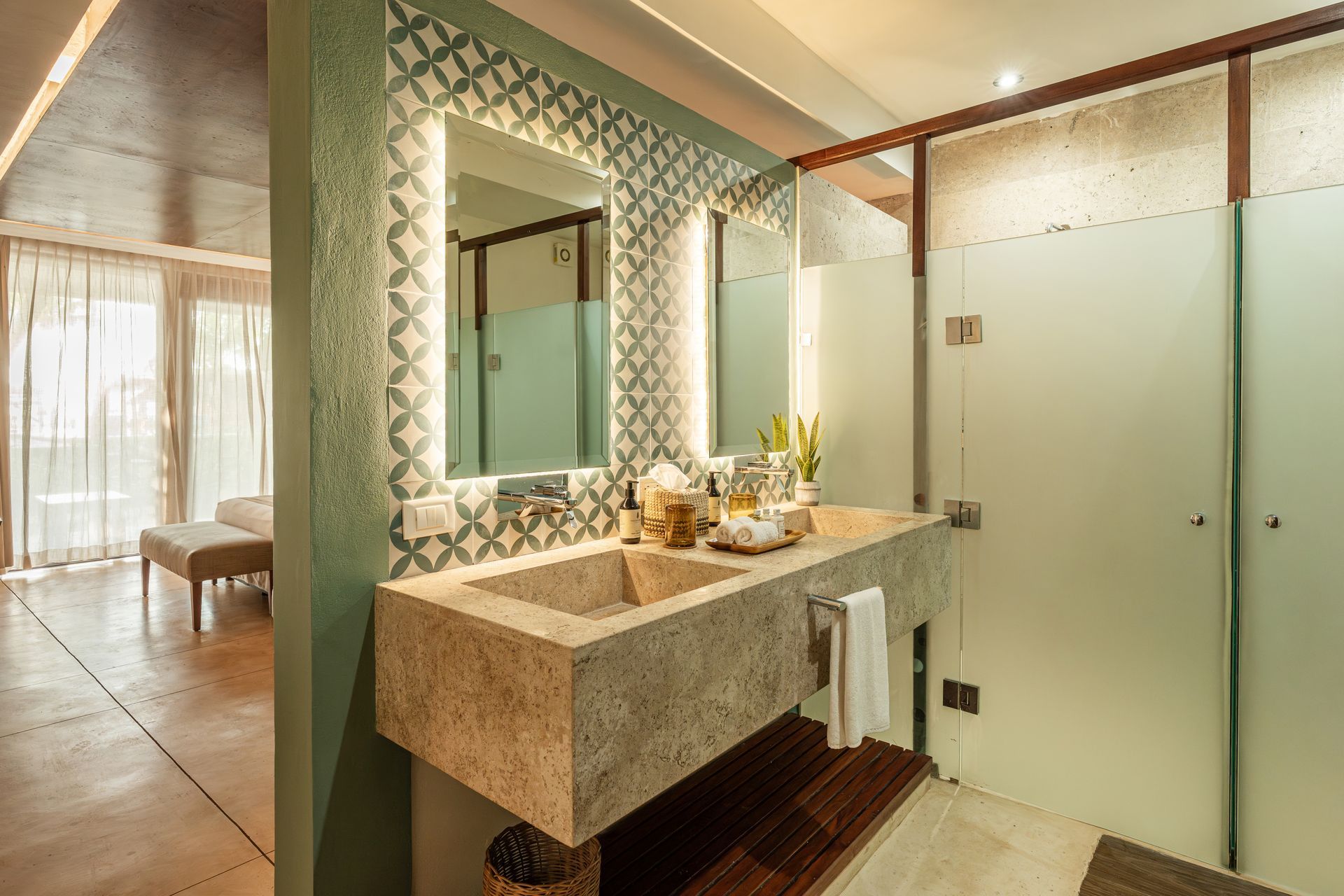 Bathroom with a stone sink, patterned wall, and frosted glass shower door.