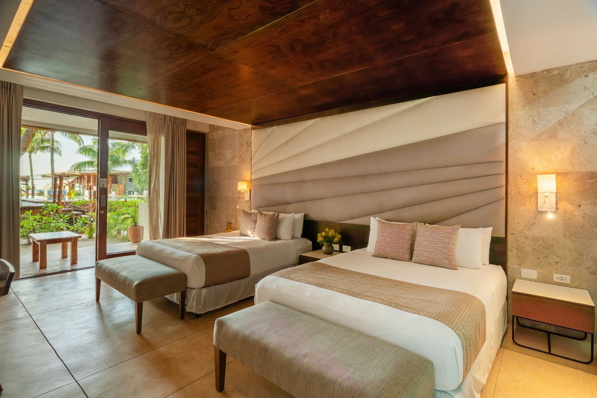 Hotel room with two queen beds, neutral color palette, balcony access.
