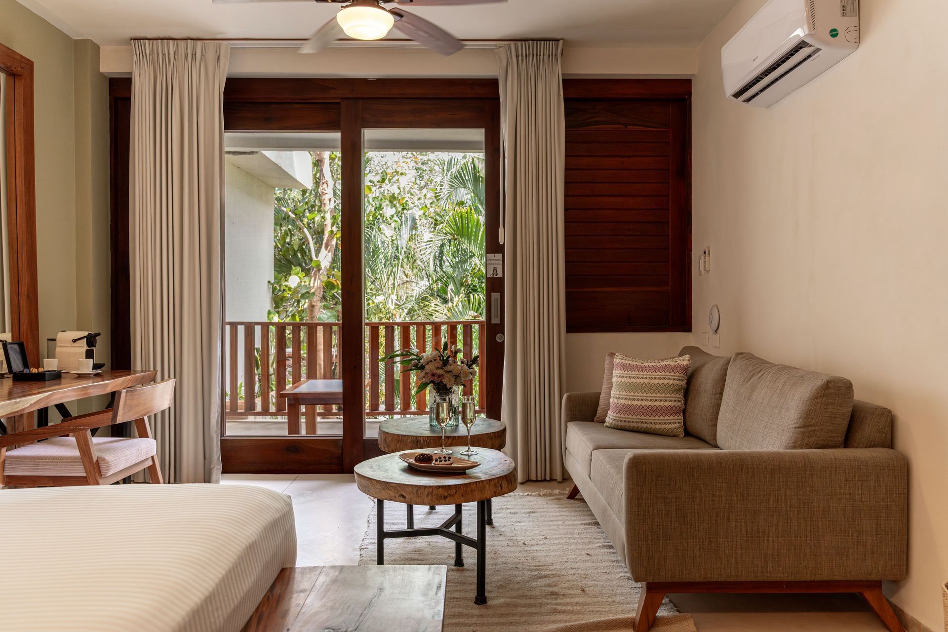Cozy living room with sliding door to balcony, sofa, small coffee tables, desk.