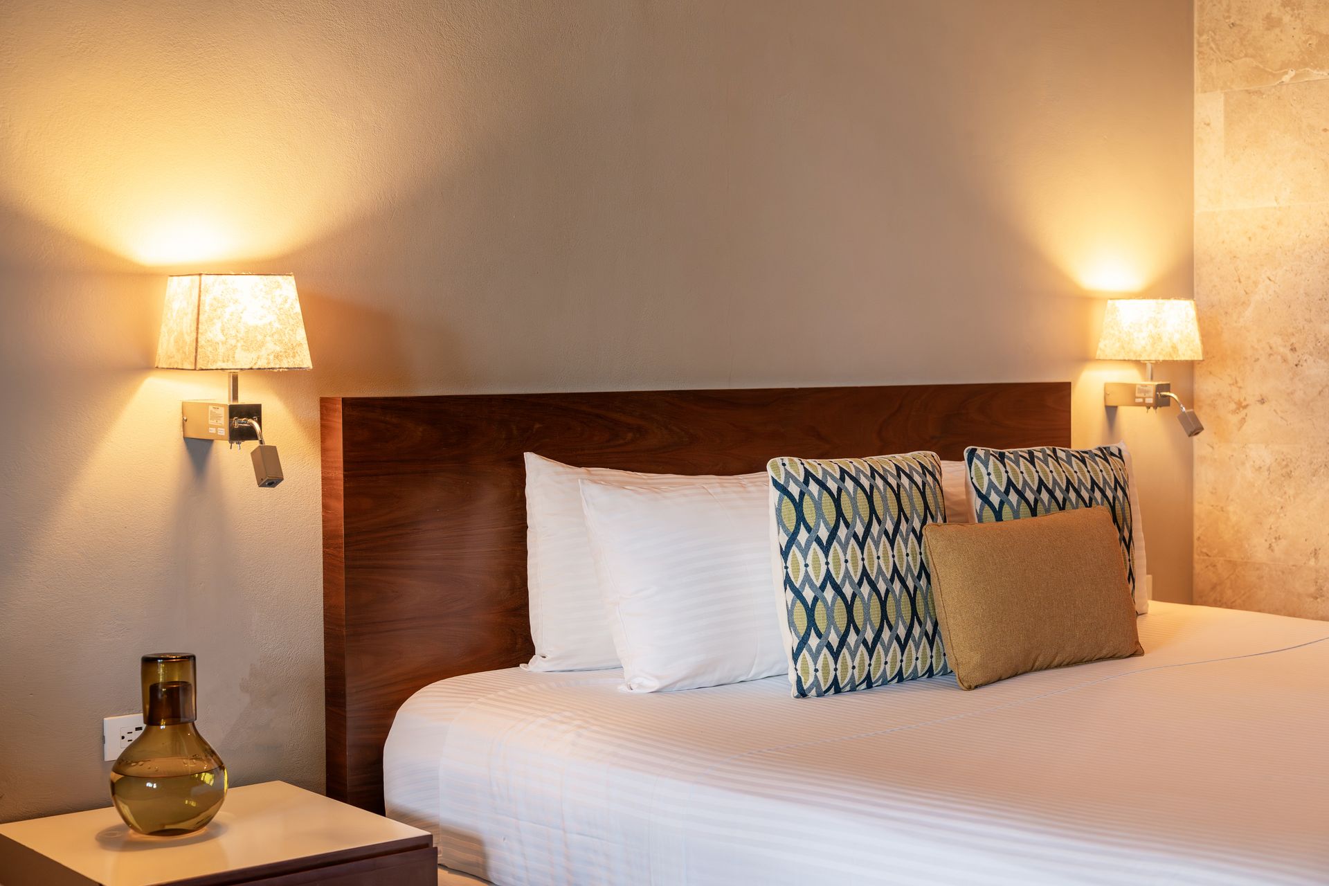 Bedroom with bed, pillows, lamps, and a nightstand.