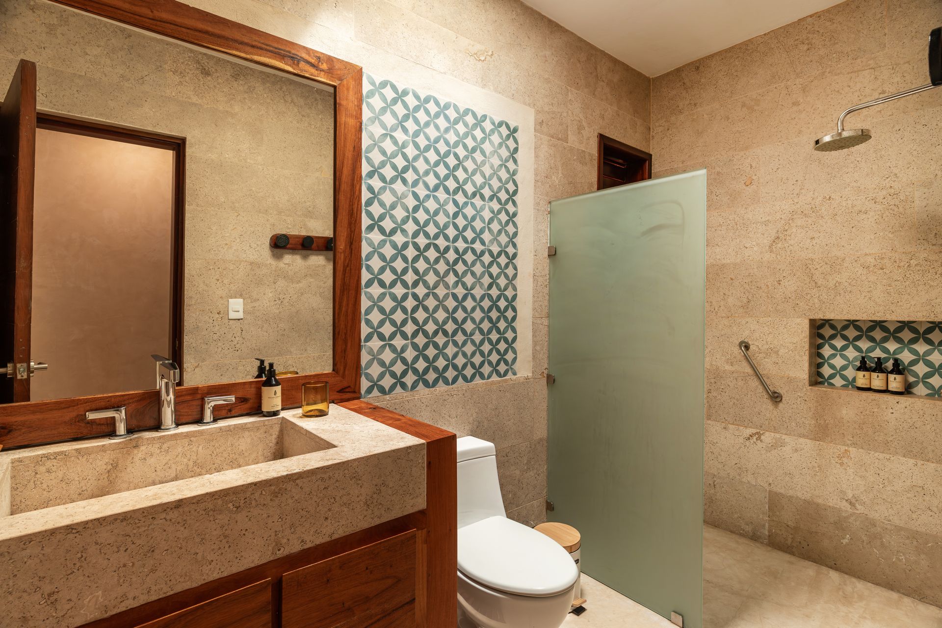 Bathroom with stone sink, wooden vanity, patterned tile accent, and frosted glass shower.