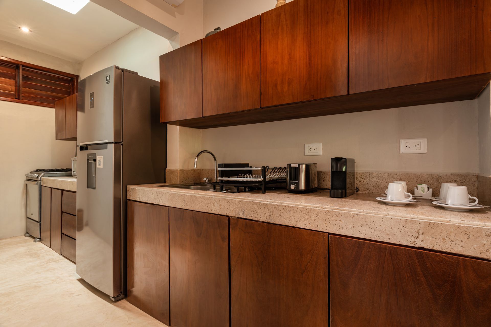 Kitchen with dark wood cabinets, stainless steel refrigerator, and countertop appliances.