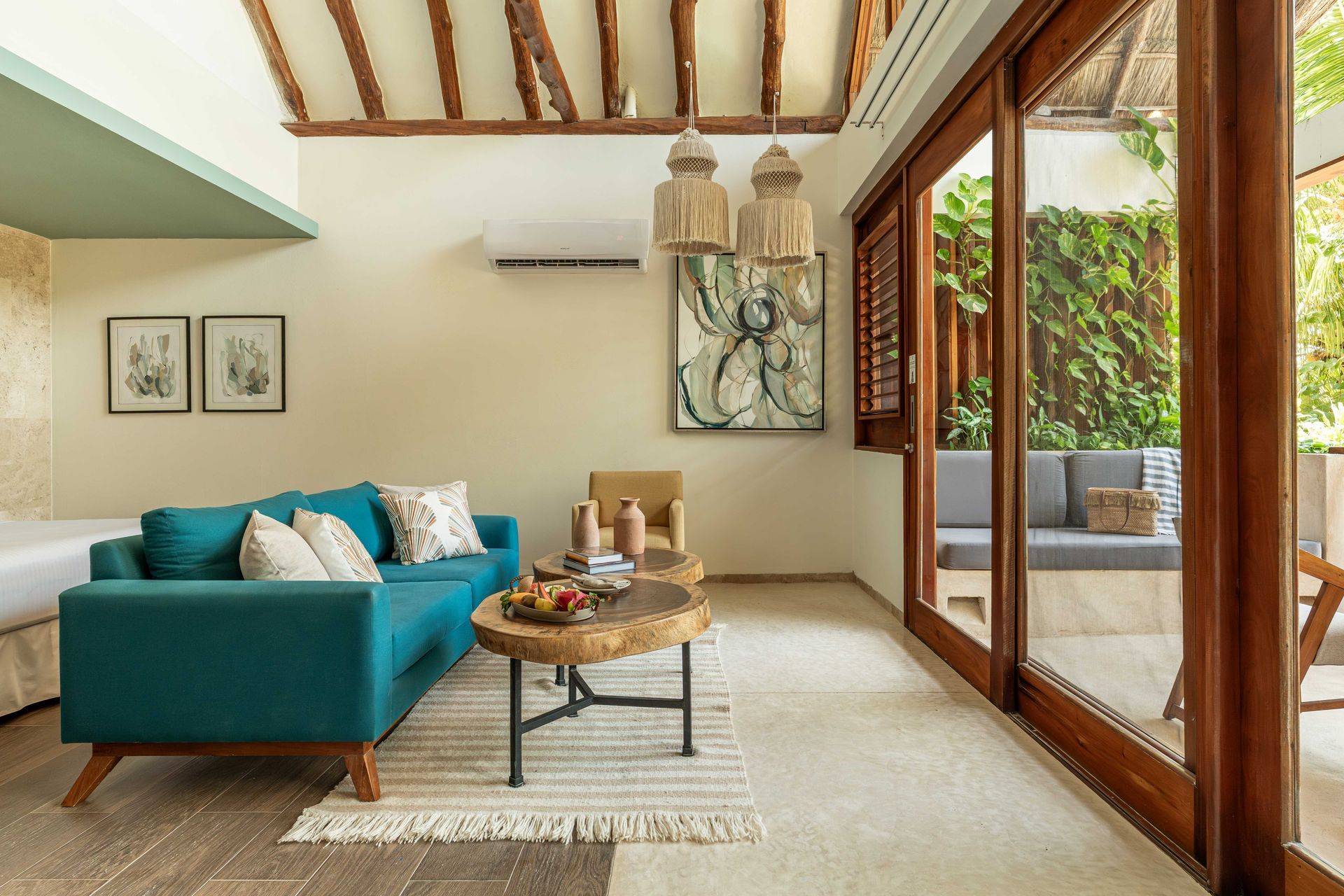 Living room with teal sofa, wooden coffee table, and large sliding door to an outdoor seating area.
