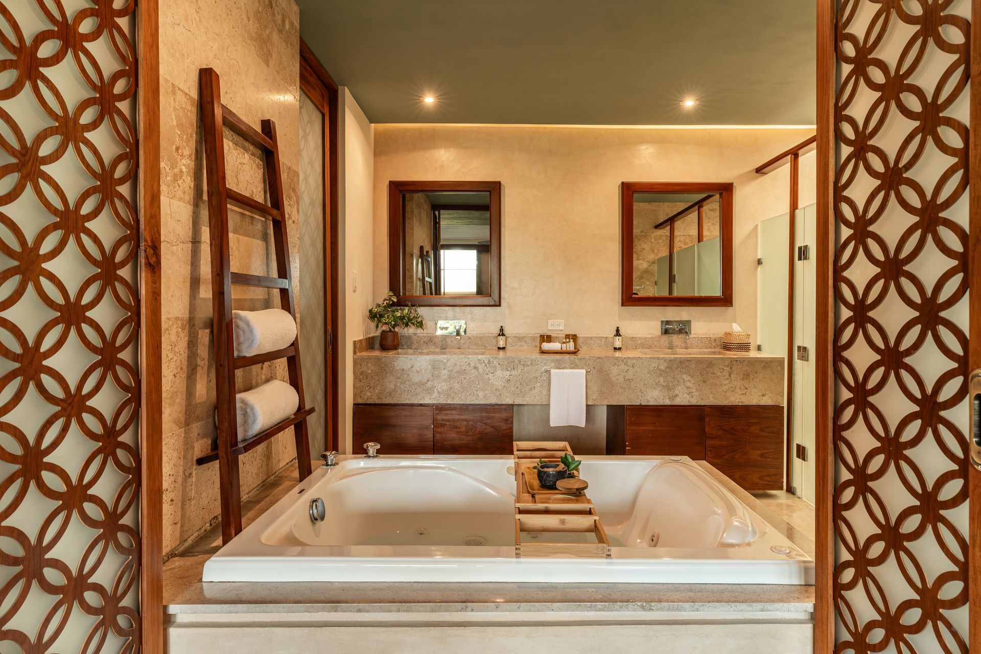 Bathroom with a large tub, towel rack, stone countertops, and decorative wooden screens.