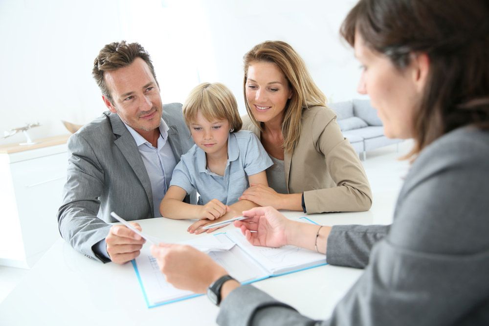 A Family is Sitting at a Table Talking to a Woman — North Coast Conveyancing In Bonny Hills, NSW
