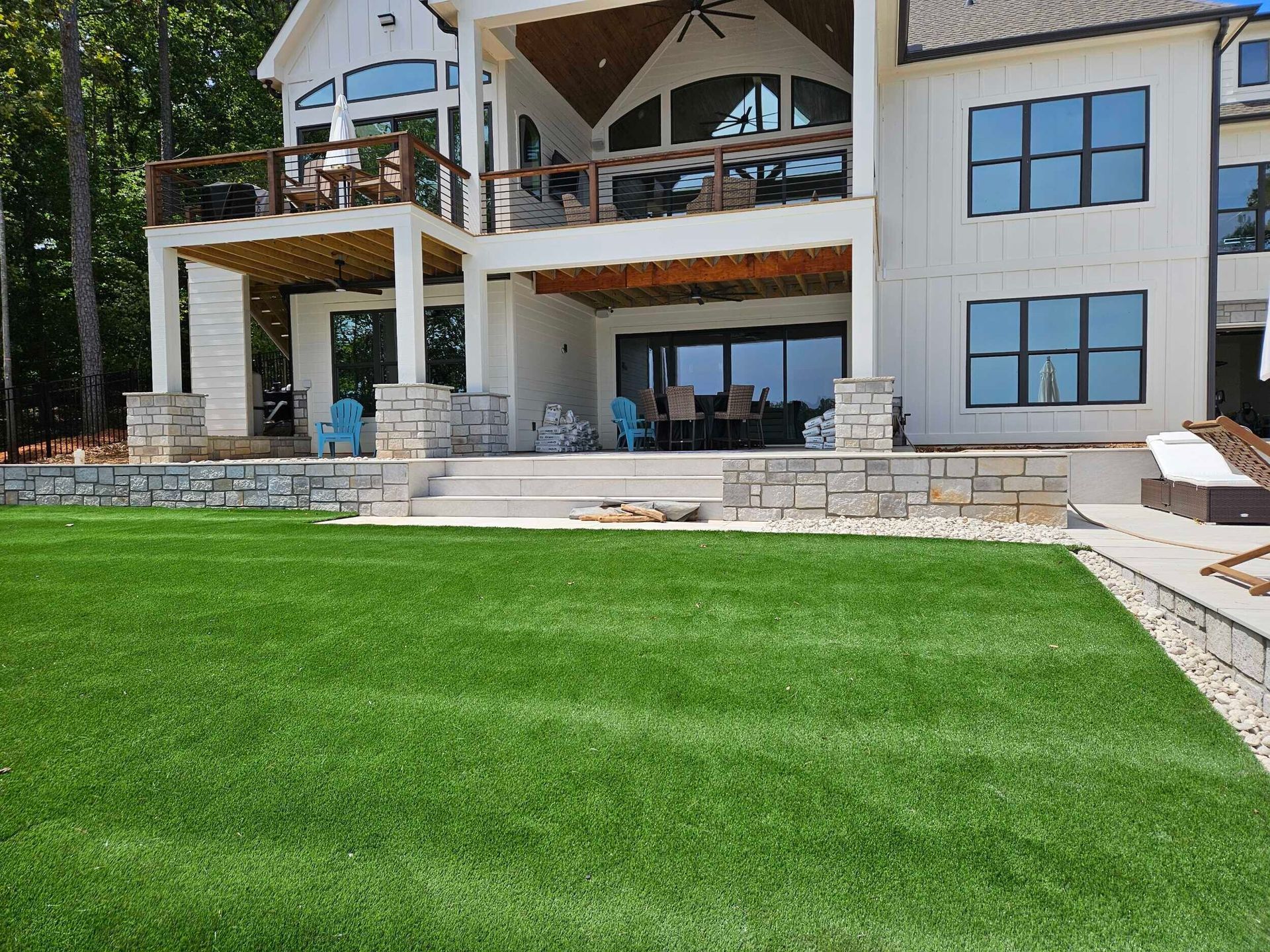 Large white house with multi-level decks and green lawn, stone accents.