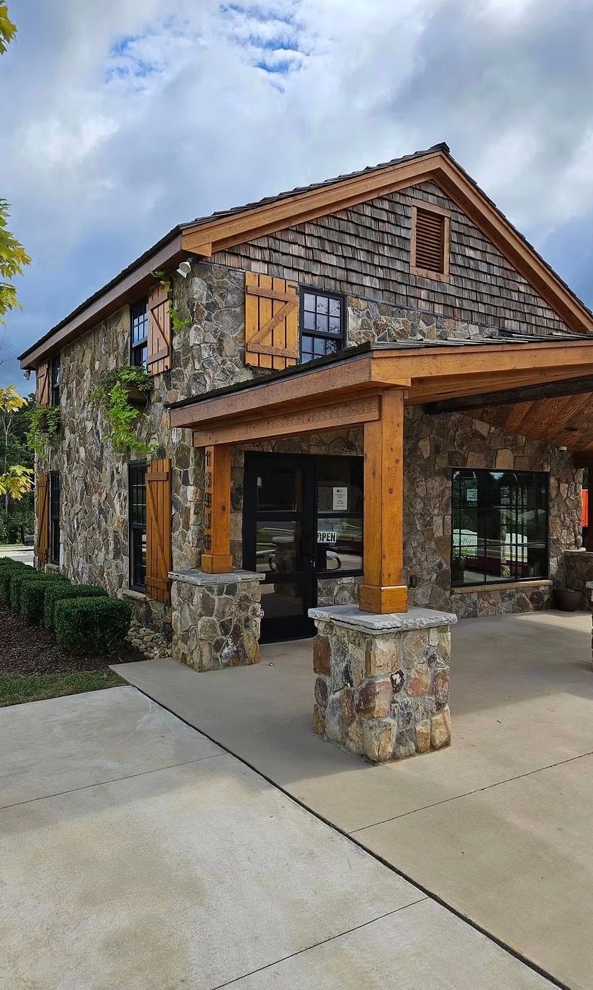 Stone building with wooden accents and shutters under a cloudy sky.