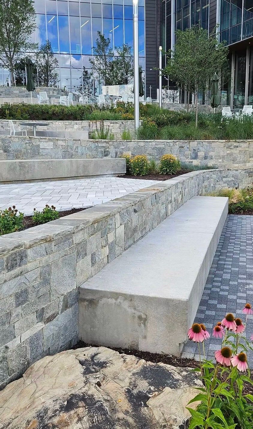 Stone steps and benches in a landscaped public area, with a modern building visible in the background.