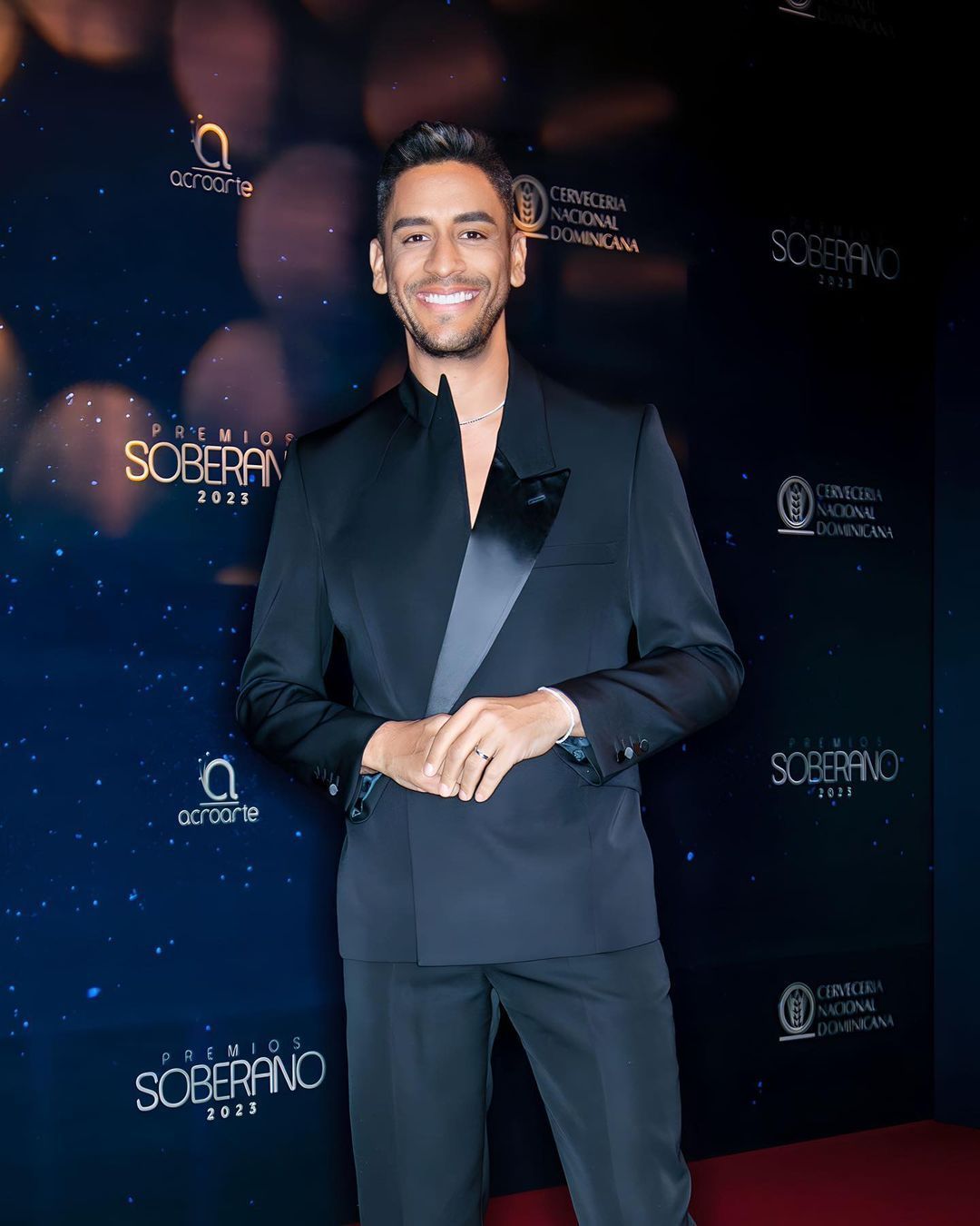 A man in a suit is standing on a red carpet.