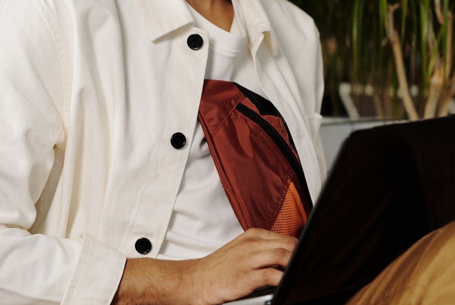 A man in a white jacket is using a laptop computer.