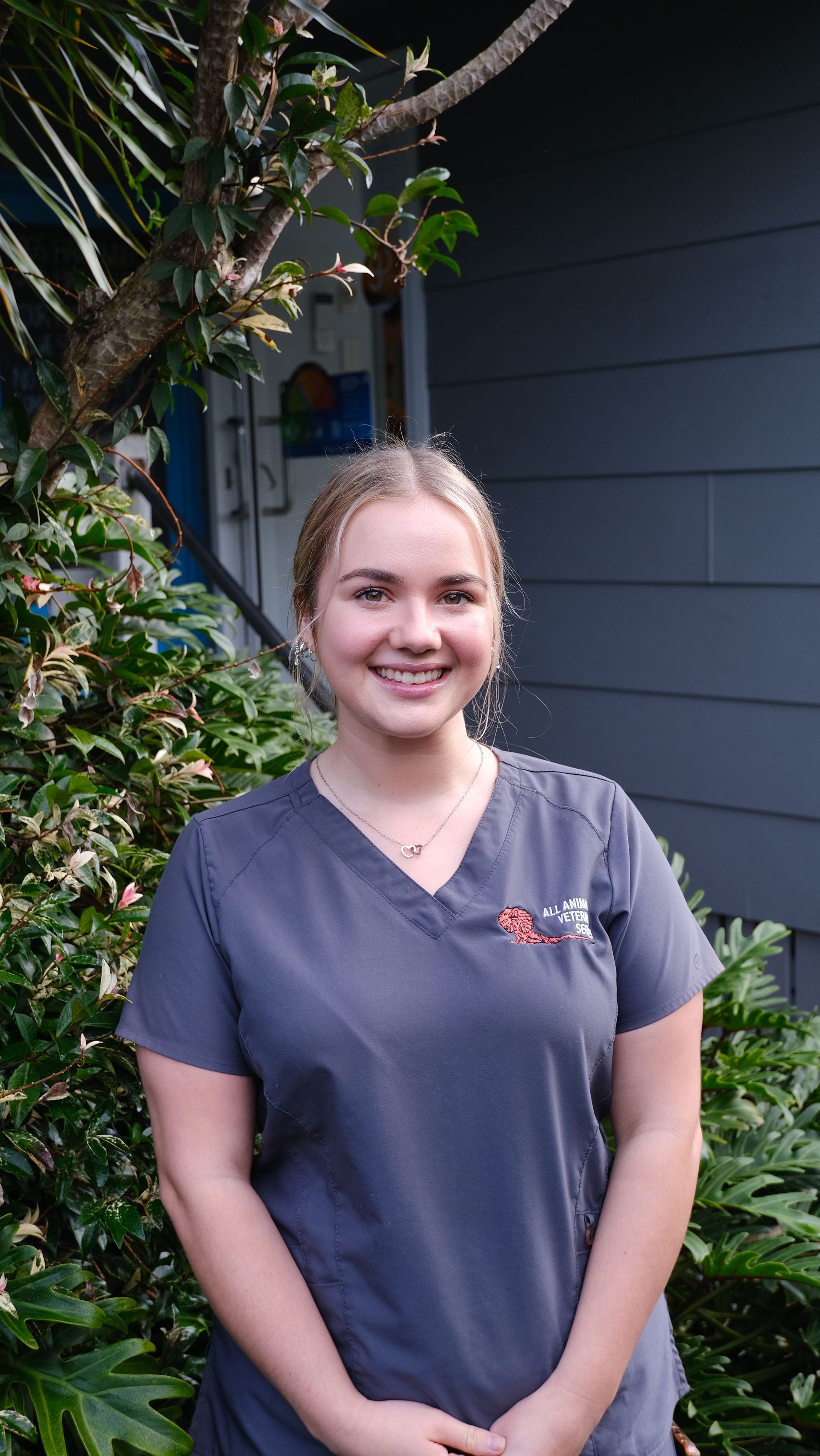 A woman in a scrub top is standing in front of a house.