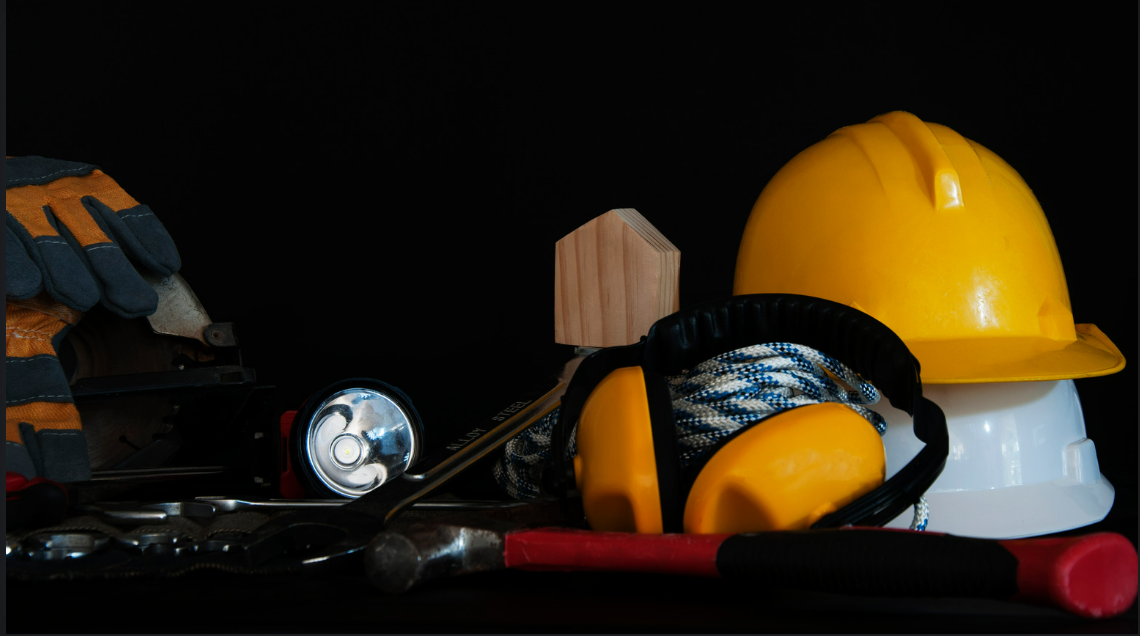 A hard hat ear muffs and gloves are on a table