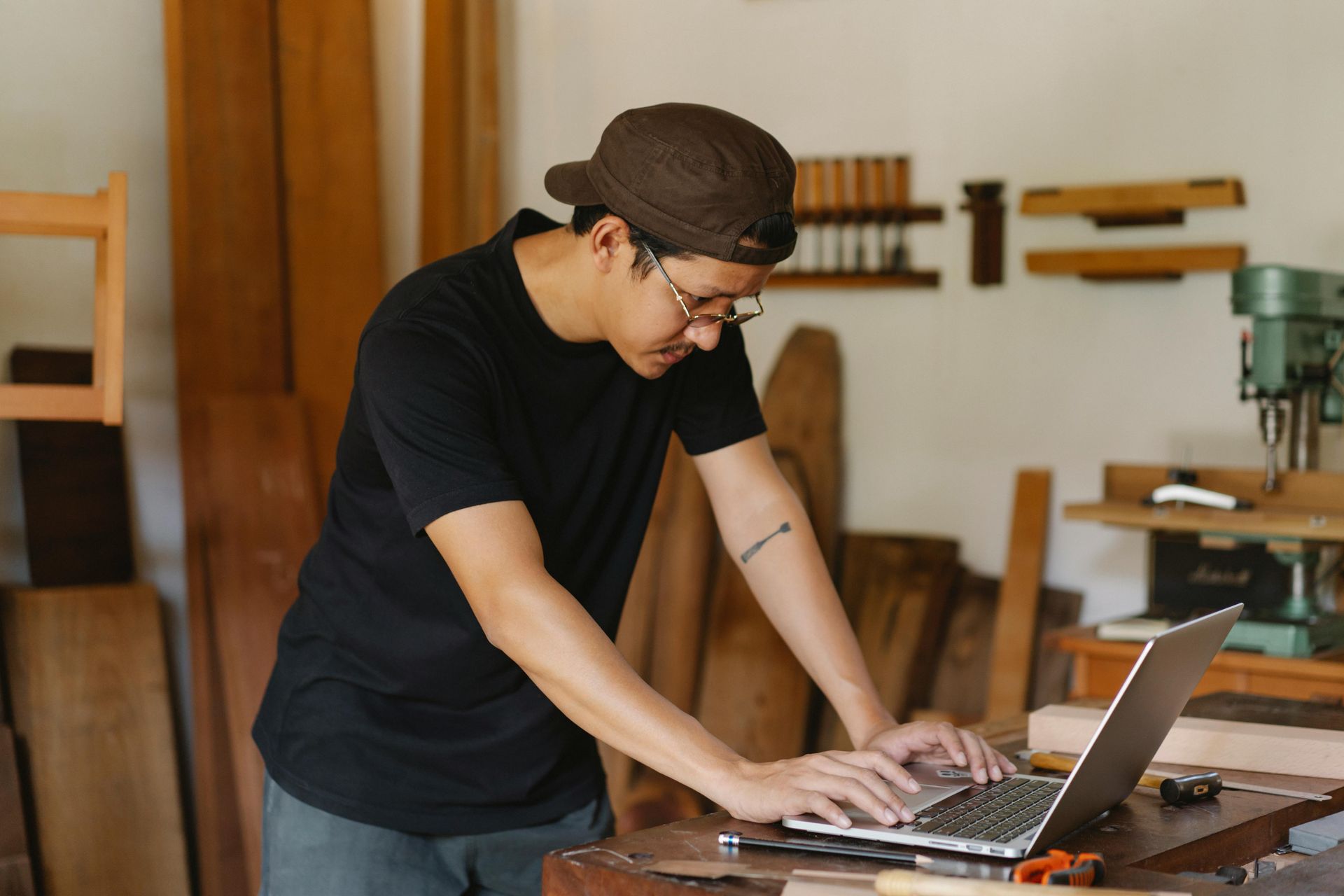 A man is using a laptop computer in a woodworking shop.