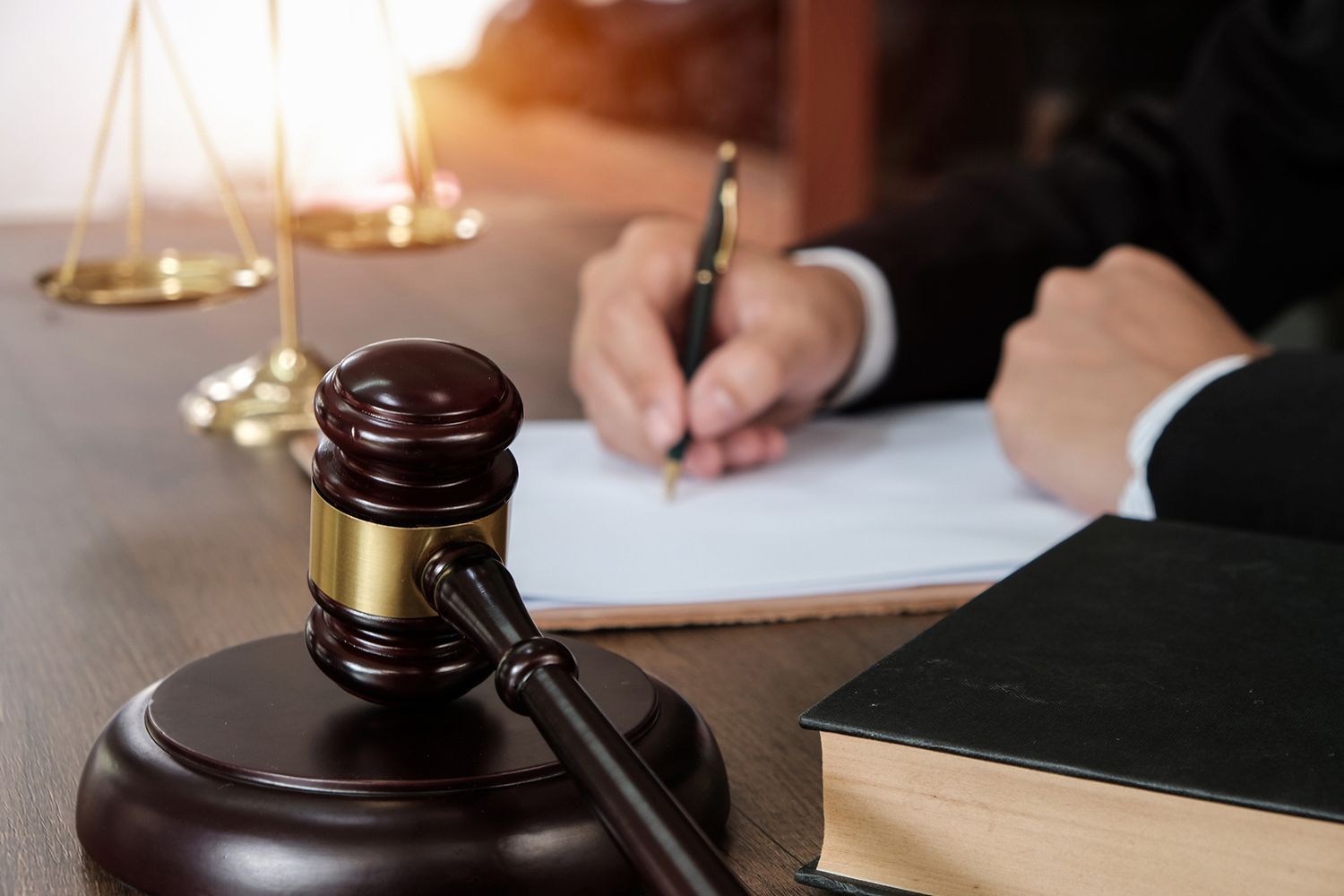 Gavel, scales and legal paperwork on desk in law office setting.