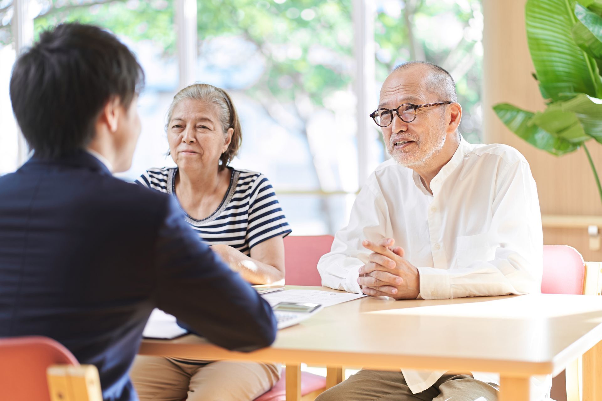 A male elder care lawyer is meeting an elderly couple in a bright office setting.