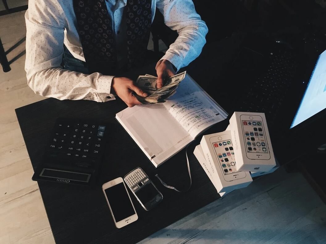 A man sitting at a desk with a laptop and a calculator
