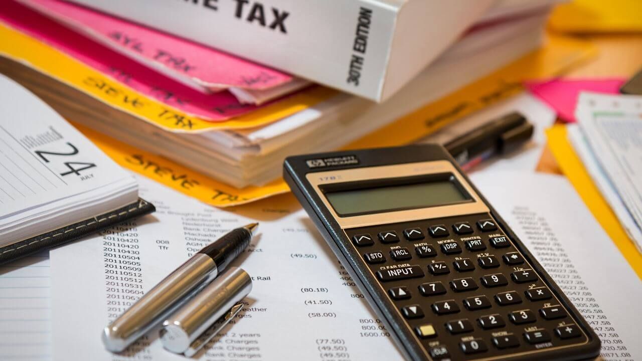 A tax calculator and financial papers on a desk.