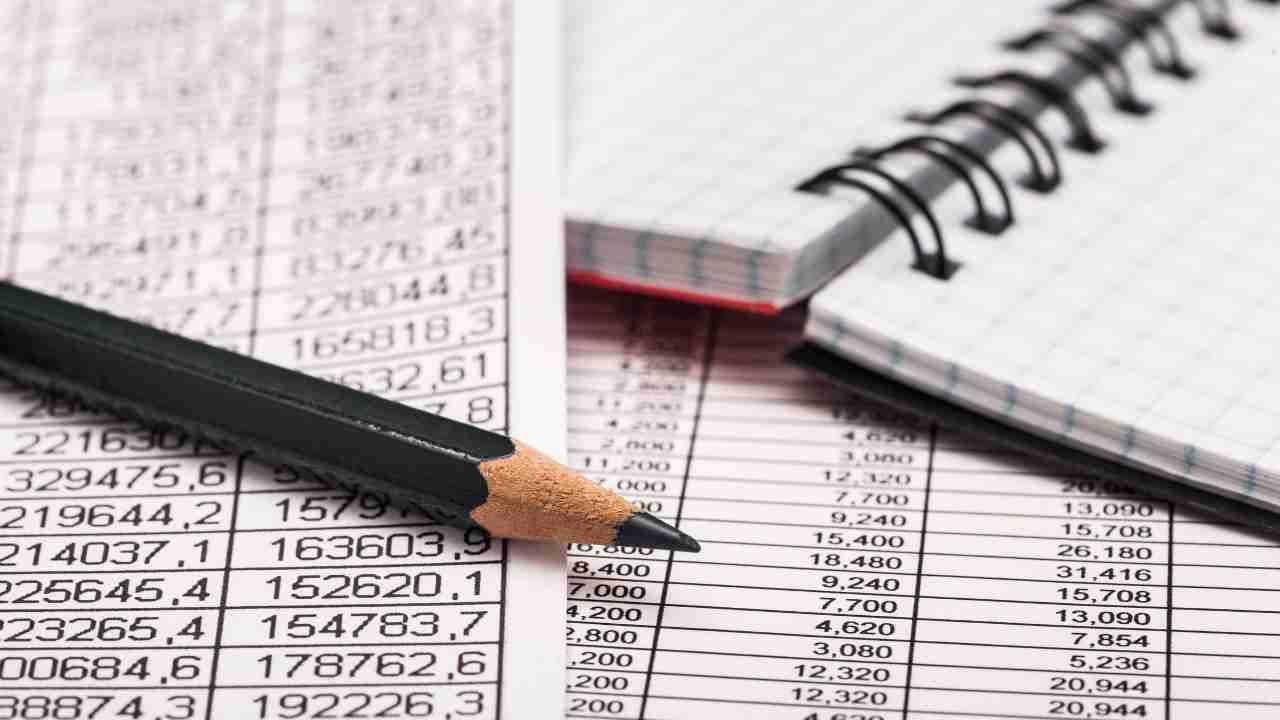 A pencil and notebook placed on top of financial documents.