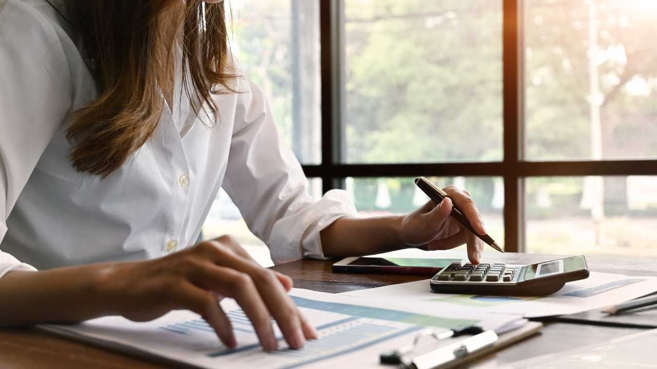 A woman engaged in calculations, using a calculator and reviewing papers.