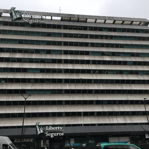 Edifício de escritórios da Liberty Seguros com fileiras horizontais de janelas; céu nublado.