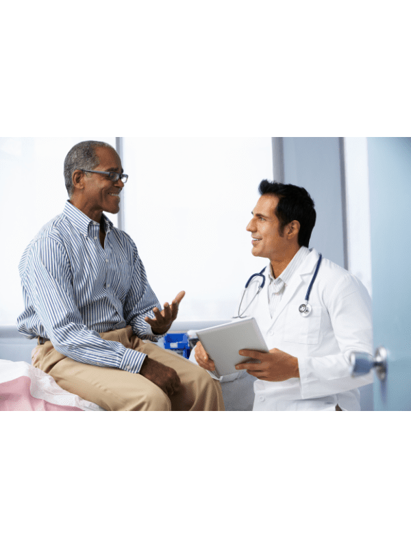 Médico de jaleco branco consulta um paciente sentado em uma maca, segurando um tablet.