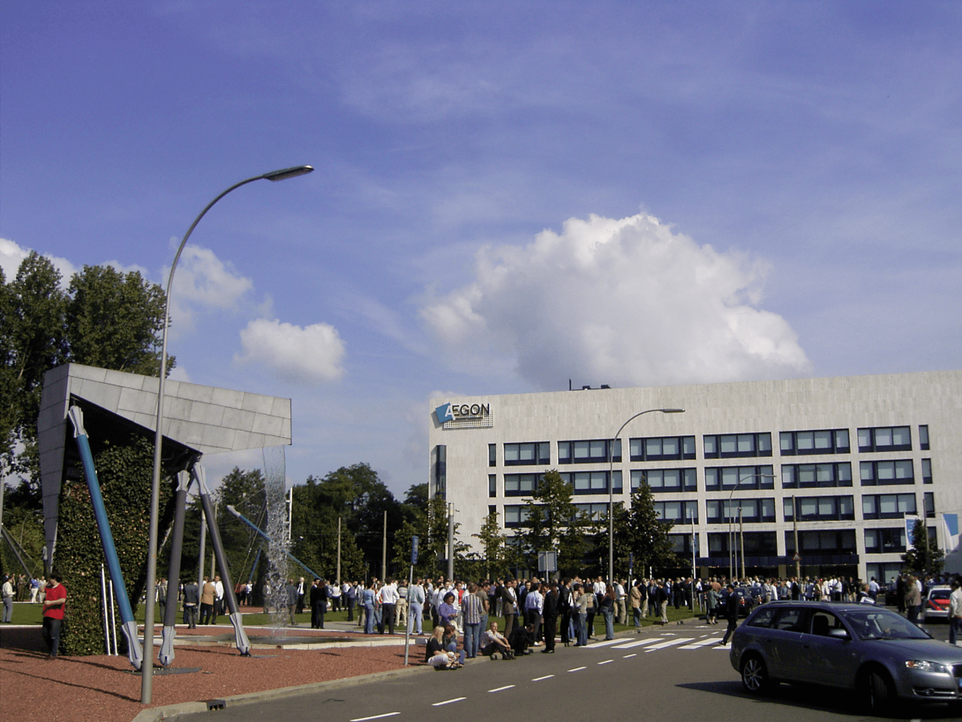Pessoas se reuniram em frente a um prédio moderno com uma placa que dizia 