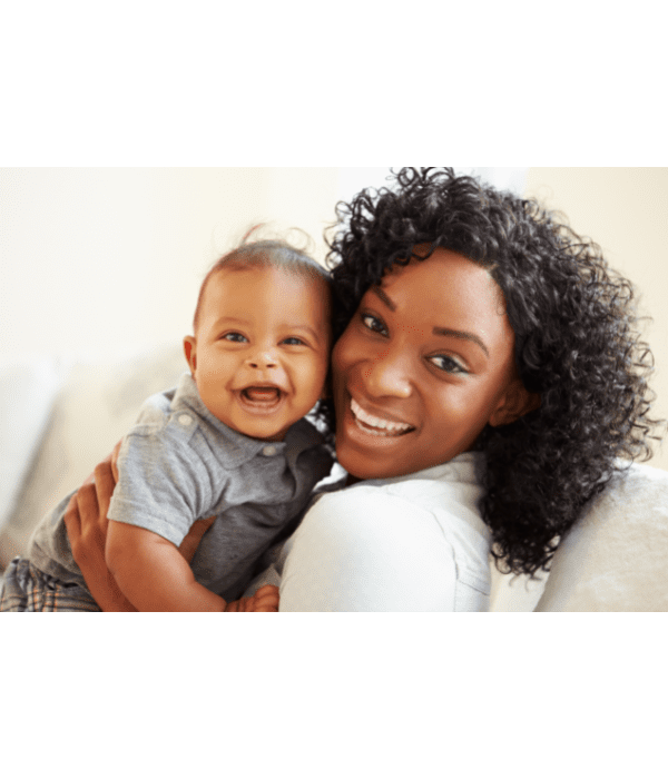 Pessoa sorridente segurando um bebê sorridente, ambos olhando para a câmera. Fundo neutro.