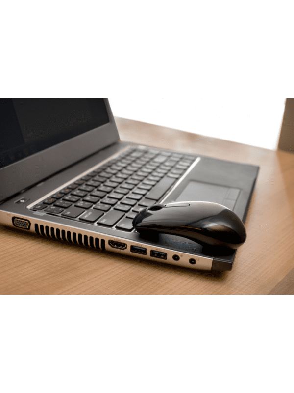 Laptop preto e mouse sobre uma superfície de madeira.