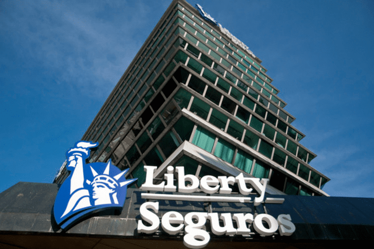 Edifício da Liberty Seguros com logotipo azul, texto branco e céu azul.