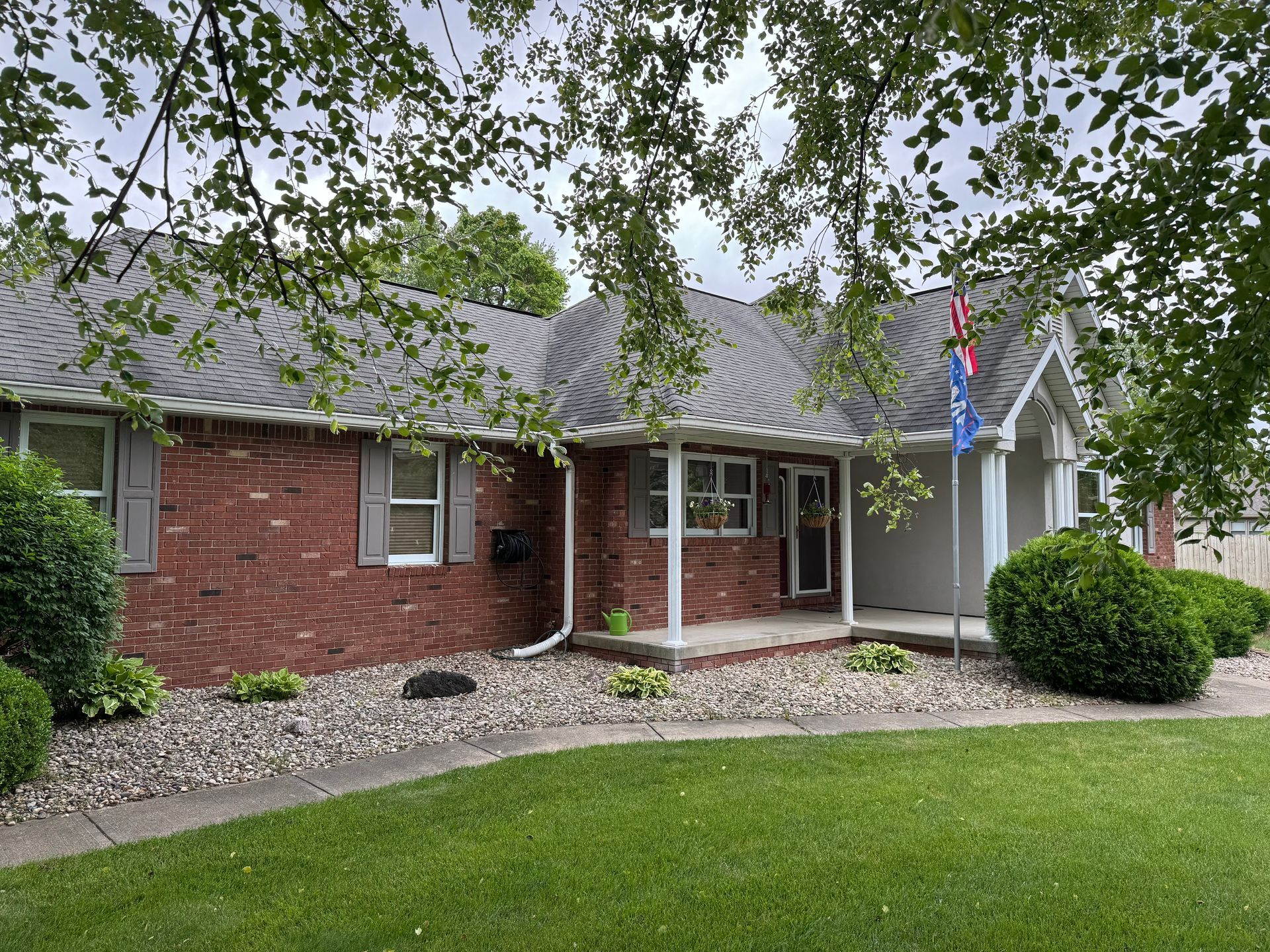 A brick house with a porch and a flag on it.