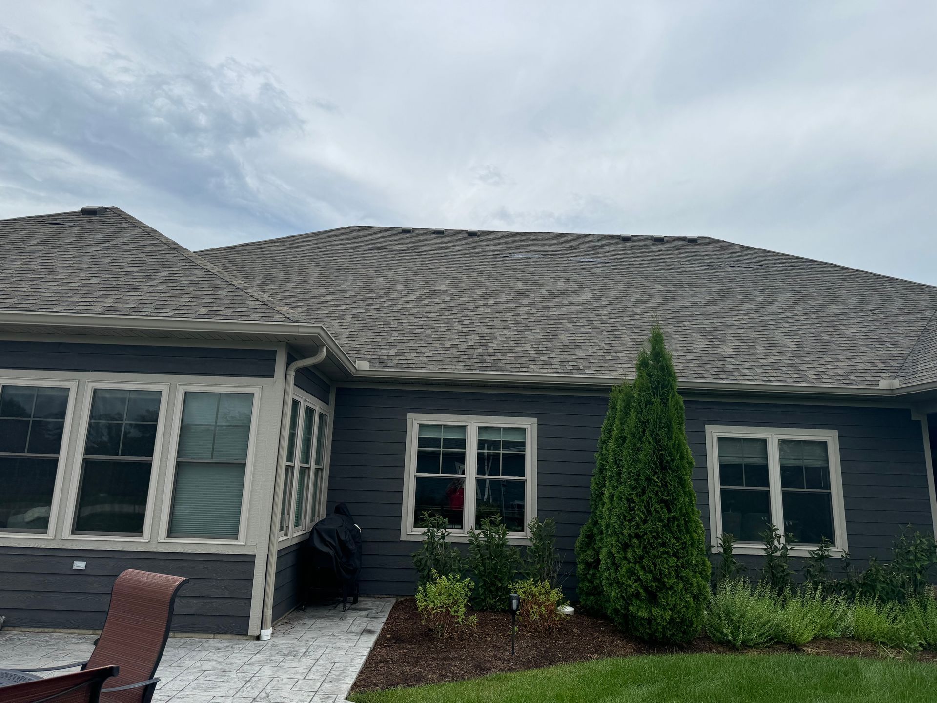 The back of a house with a gray roof and white windows.