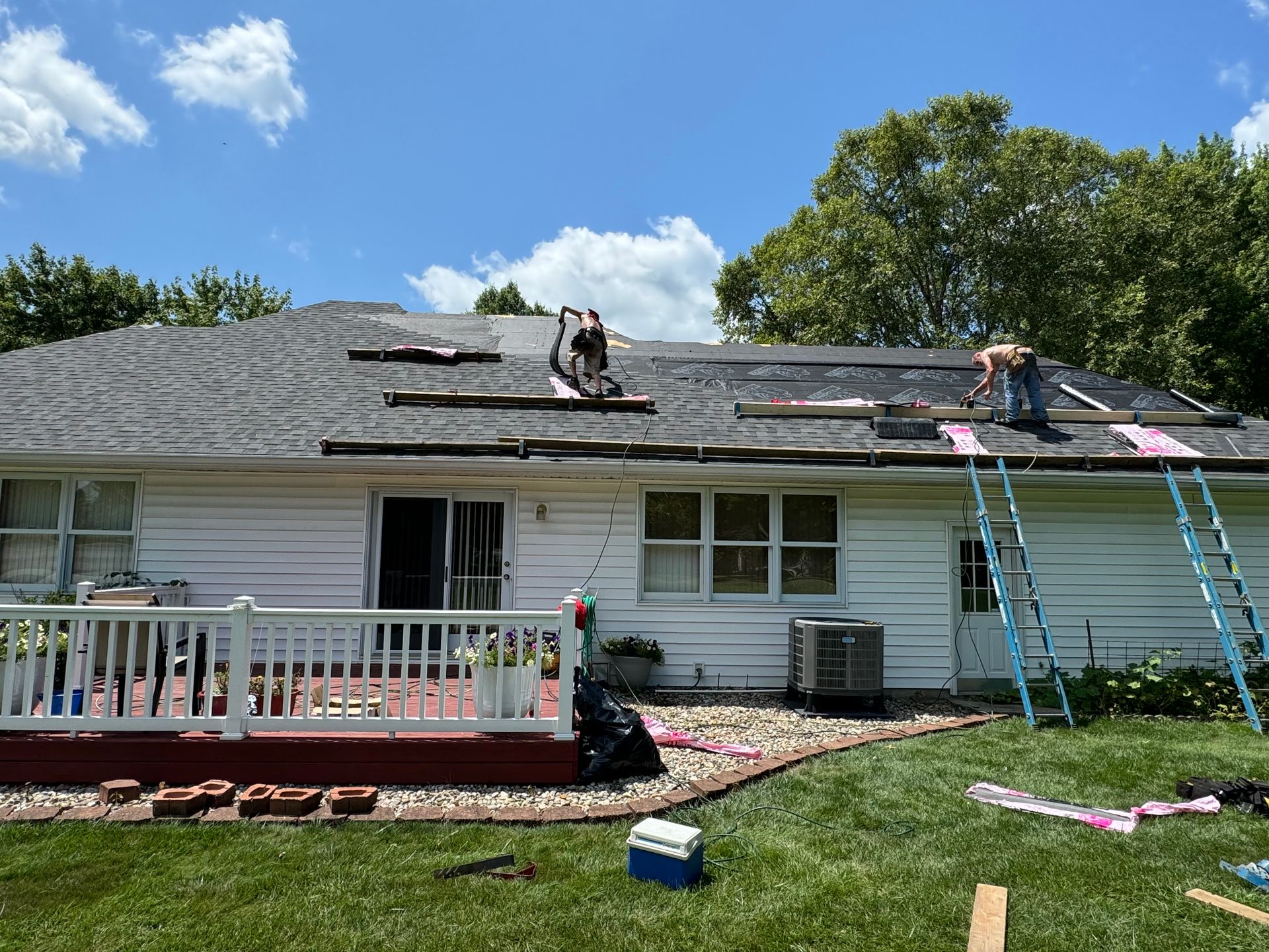 A couple of men are working on the roof of a house.