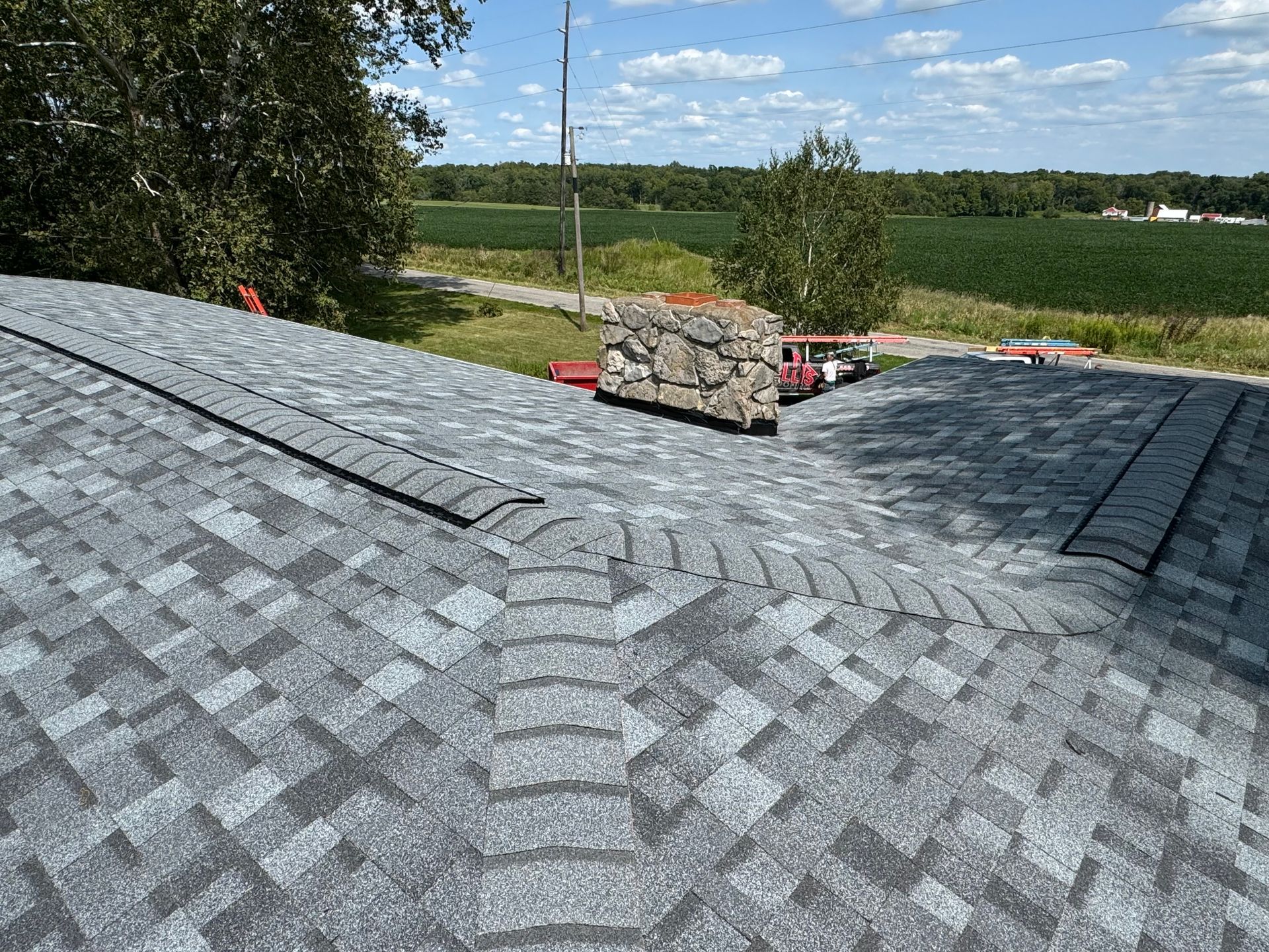 A roof with a lot of shingles on it and a field in the background.