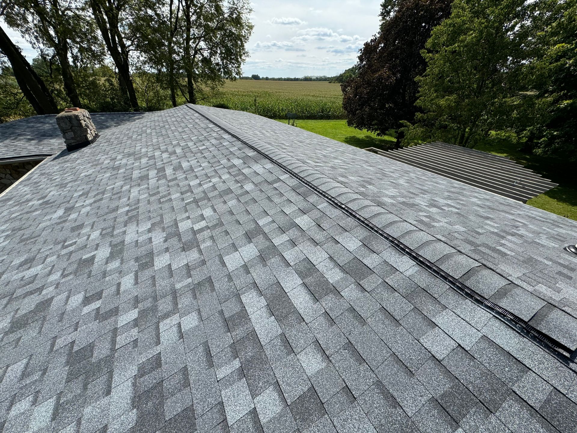 A roof with a lot of shingles on it and trees in the background.