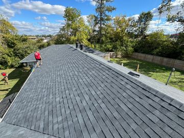 A group of people are working on the roof of a house.