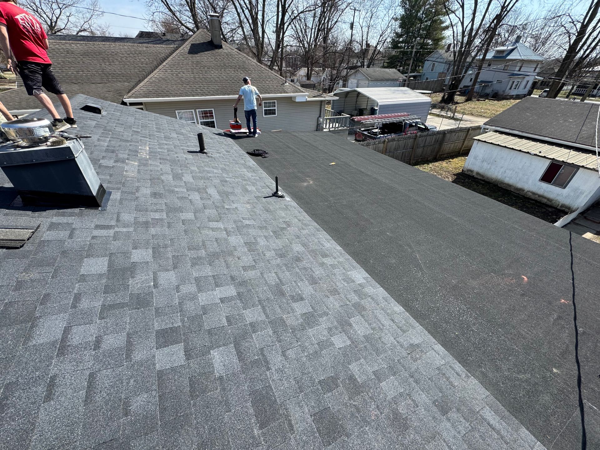Two men are working on the roof of a house.