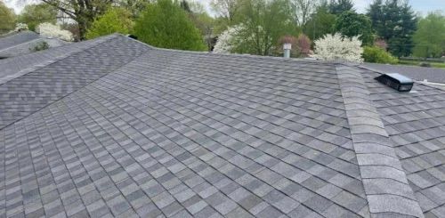 A roof with a lot of shingles on it and trees in the background.