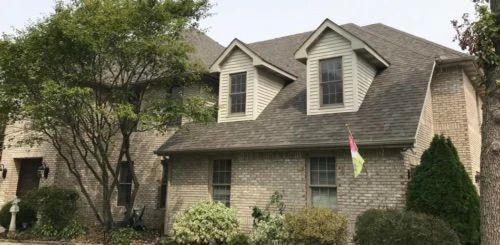 A large brick house with a gray roof and a flag in front of it.