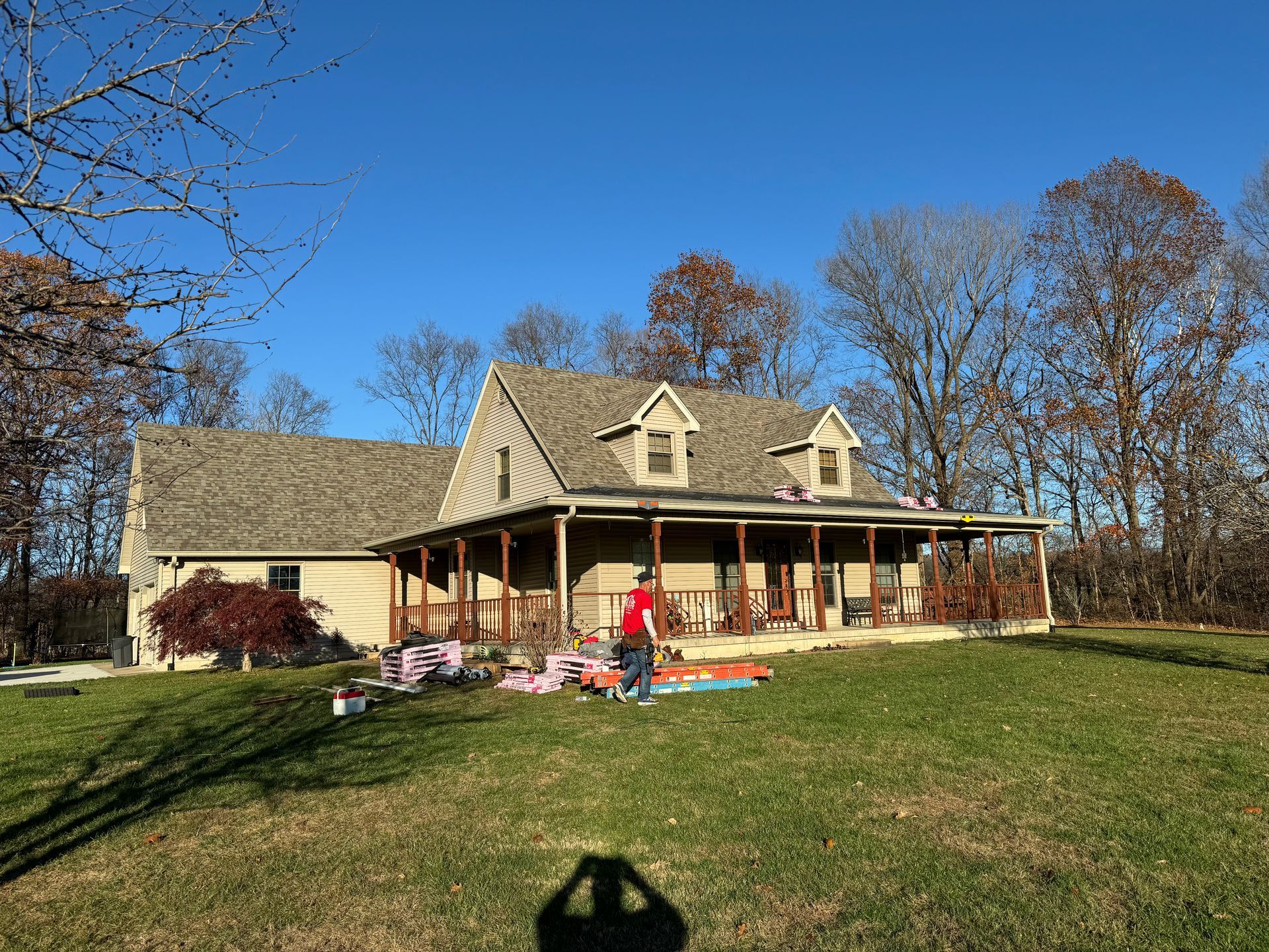A man is standing in front of a house with a porch.