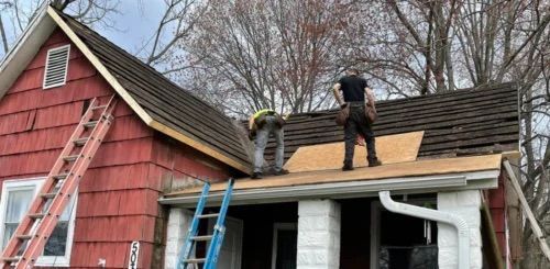 Two men are working on the roof of a house.