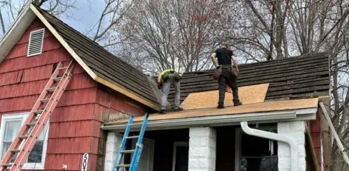 Two men are working on the roof of a house.