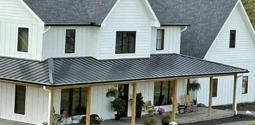 A white house with a black roof and a porch.