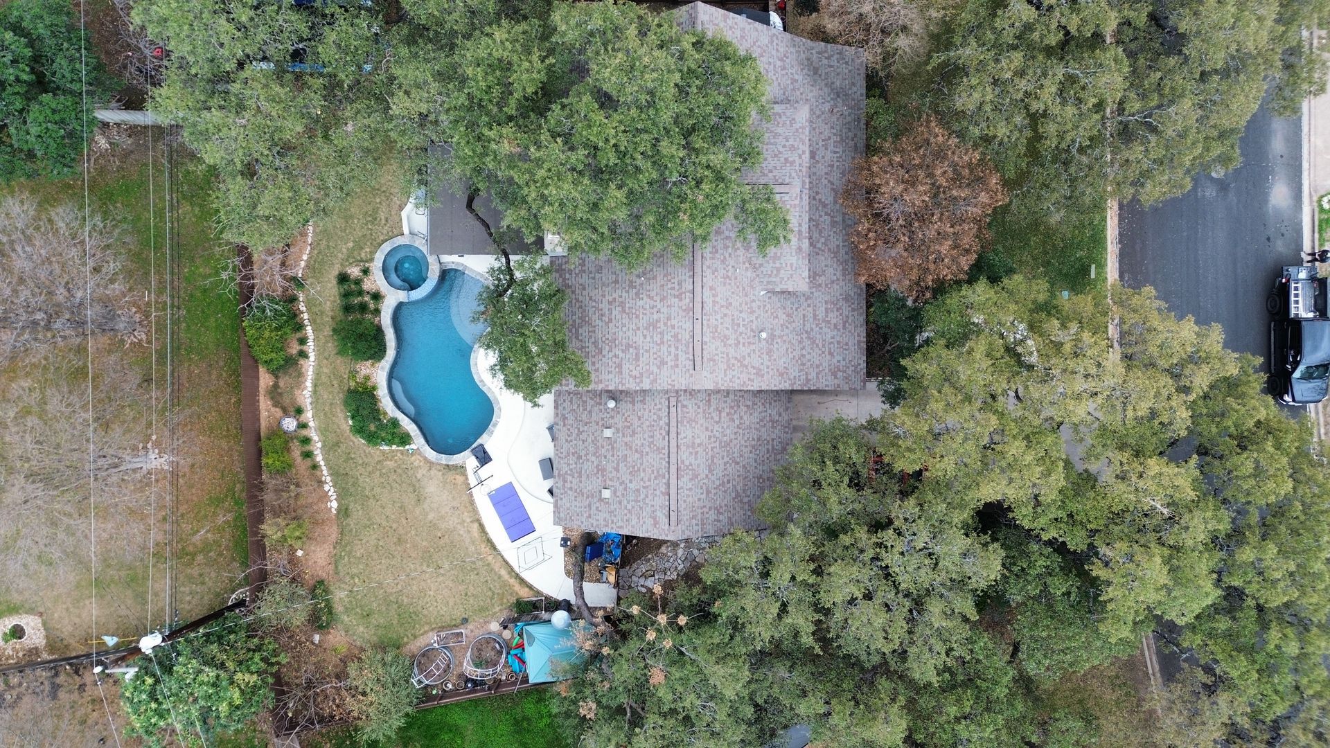 Aerial view of a house with a pool, surrounded by trees and grass.