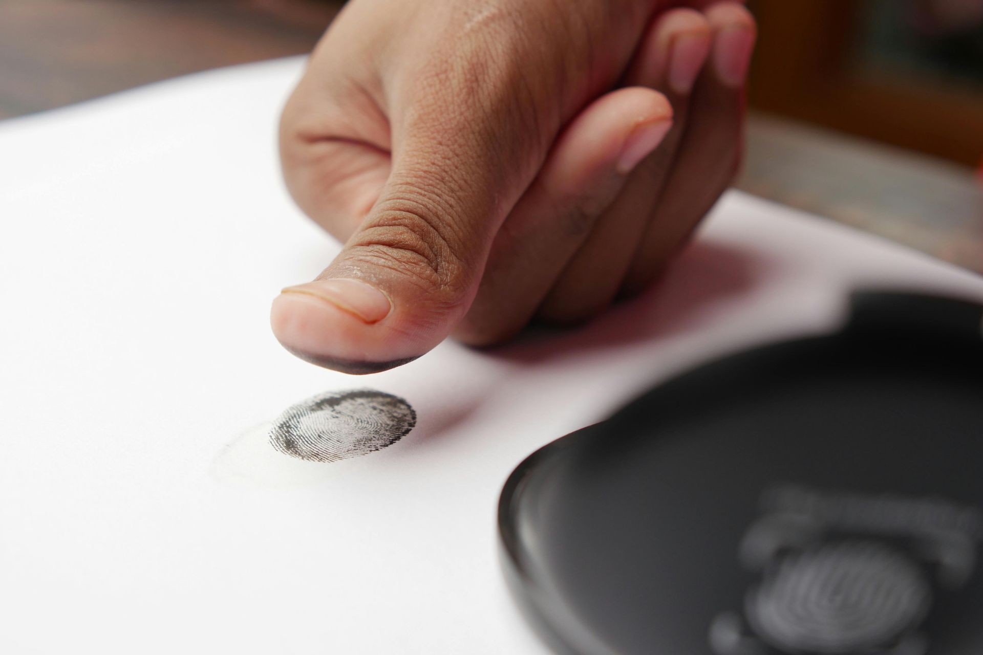 A person 's finger is pointing at a fingerprint on a piece of paper