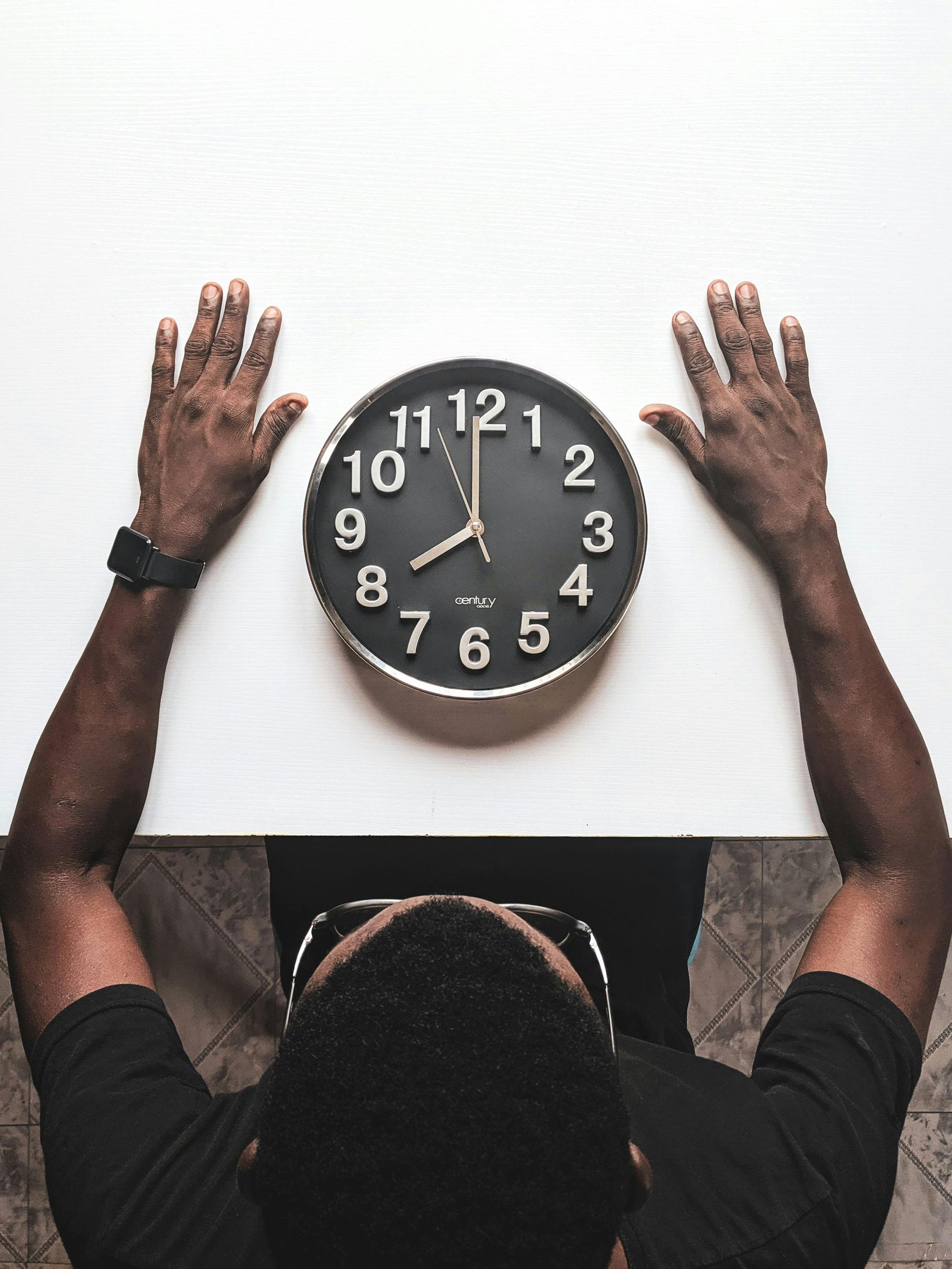 A man is reaching for a clock that shows the time as 4:20