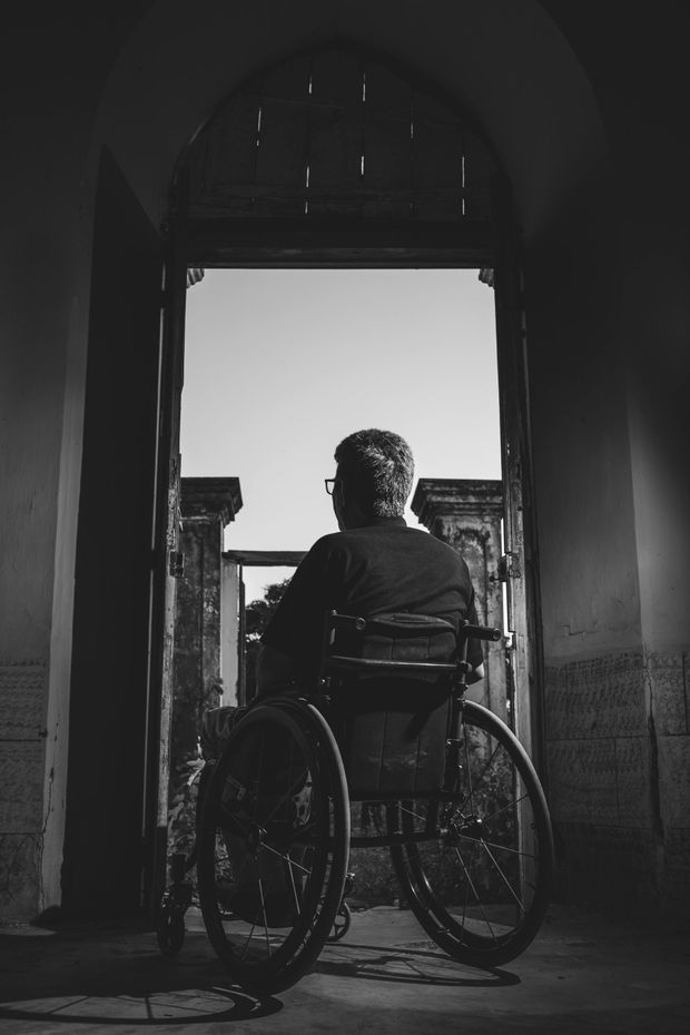 A man in a wheelchair is looking out of a doorway.