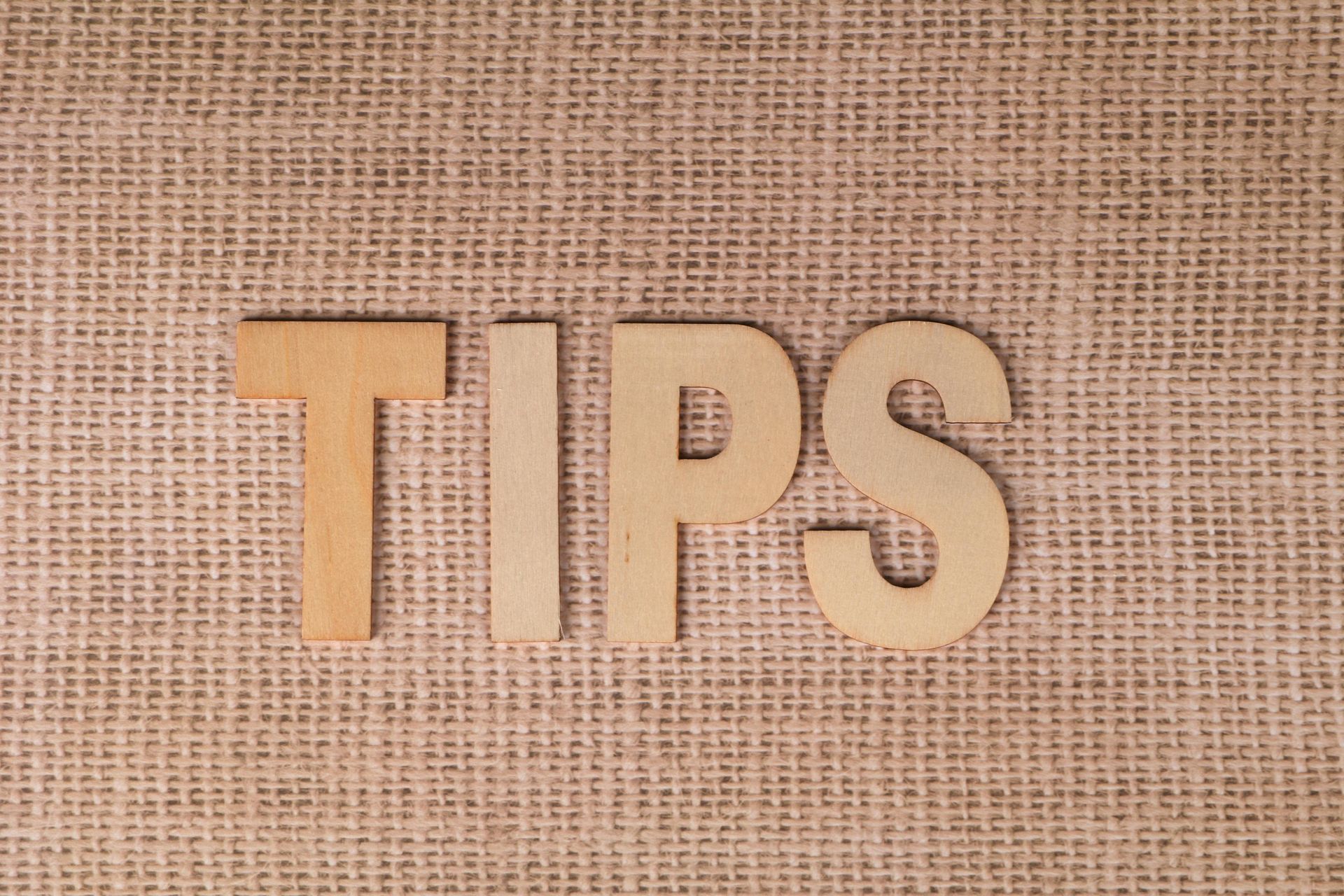 Wooden letters spelling “TIPS” on a burlap background